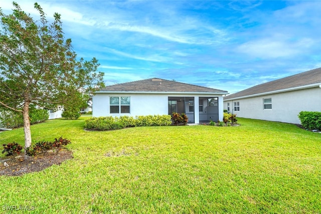 rear view of property featuring a lawn and a sunroom