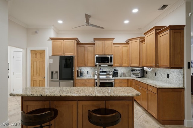 kitchen featuring a breakfast bar area, ceiling fan, stainless steel appliances, and light stone counters