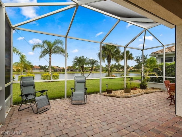 view of patio featuring glass enclosure and a water view