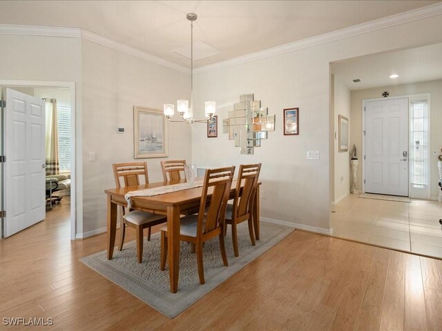 dining space featuring light wood-style floors, baseboards, ornamental molding, and an inviting chandelier