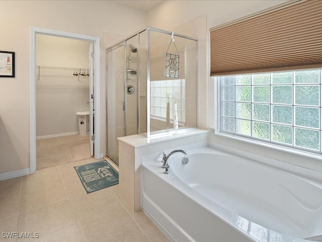 bathroom with a spacious closet, a shower stall, a bath, baseboards, and tile patterned floors