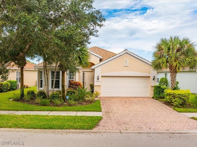 view of front of home featuring a garage, decorative driveway, a tile roof, and stucco siding