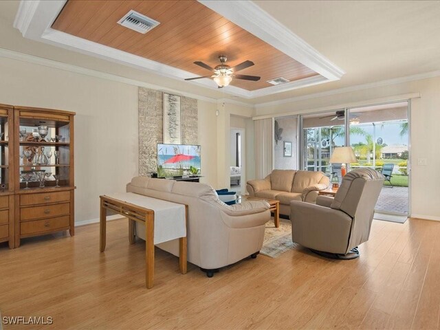 living area with crown molding, light wood finished floors, a raised ceiling, visible vents, and wooden ceiling