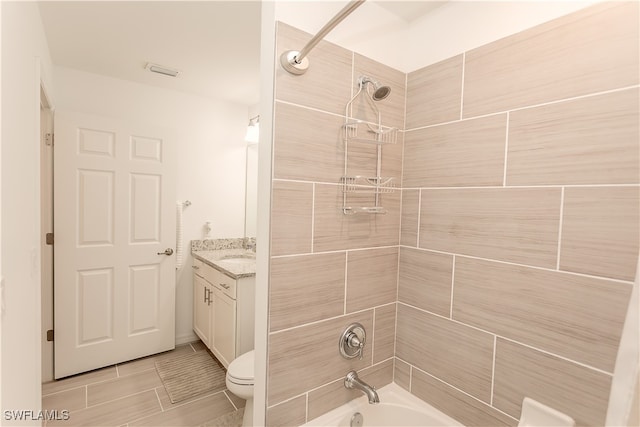 full bathroom featuring tiled shower / bath, vanity, and toilet