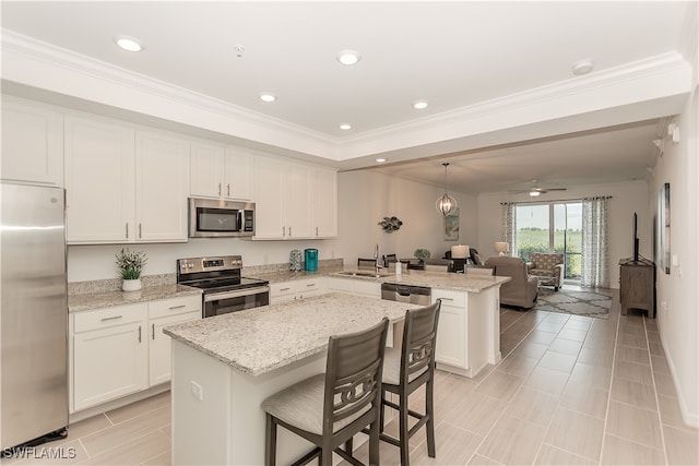 kitchen with ceiling fan, pendant lighting, stainless steel appliances, a center island, and light stone countertops