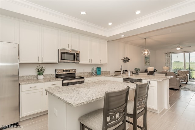 kitchen featuring a breakfast bar, pendant lighting, stainless steel appliances, a center island, and ceiling fan