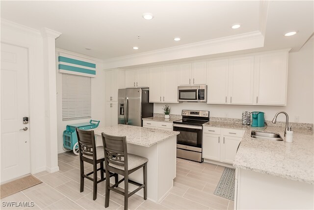 kitchen featuring light stone counters, sink, a kitchen island, white cabinetry, and stainless steel appliances