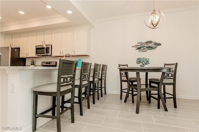 kitchen with light stone countertops, stainless steel appliances, white cabinets, and a breakfast bar area