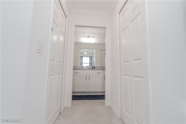 hall with ornamental molding, sink, and light carpet