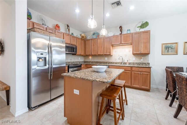 kitchen featuring sink, hanging light fixtures, a kitchen island, a kitchen breakfast bar, and appliances with stainless steel finishes