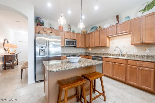 kitchen featuring a breakfast bar, sink, a kitchen island, decorative backsplash, and stainless steel appliances