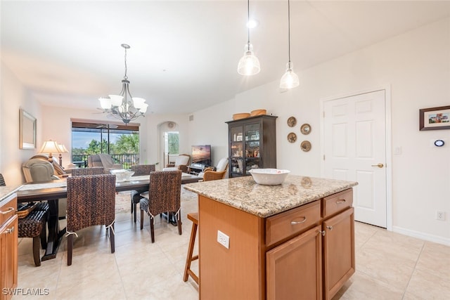 kitchen with light stone counters, pendant lighting, light tile patterned floors, a kitchen island, and a chandelier