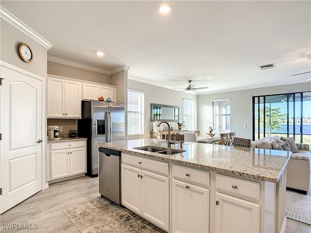 kitchen with appliances with stainless steel finishes, an island with sink, white cabinetry, and sink