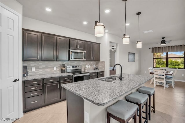 kitchen featuring a center island with sink, sink, ceiling fan, appliances with stainless steel finishes, and decorative light fixtures