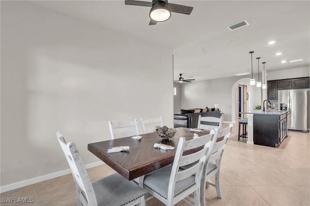 tiled dining space with ceiling fan and sink