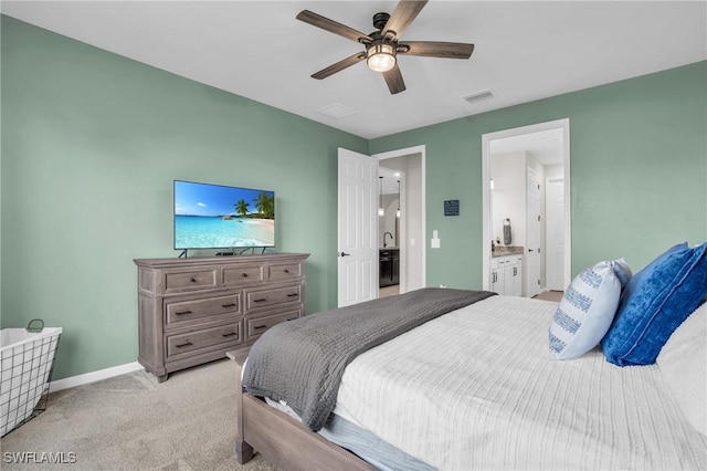 bedroom featuring ceiling fan, light colored carpet, and connected bathroom