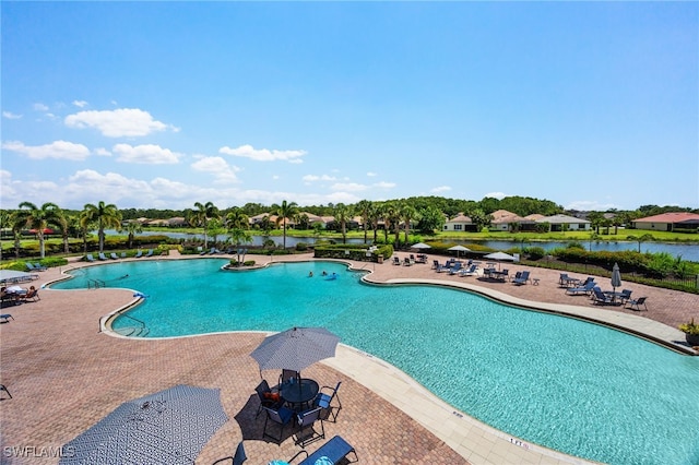 view of swimming pool featuring a patio and a water view