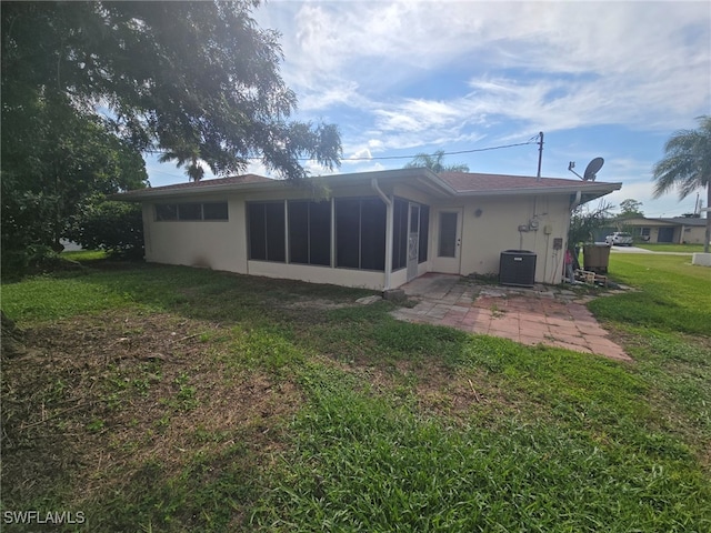 back of property with a lawn, a patio, a sunroom, and central air condition unit