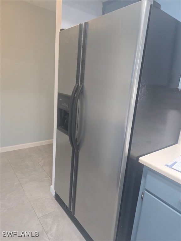 interior space featuring stainless steel refrigerator with ice dispenser and light tile patterned floors