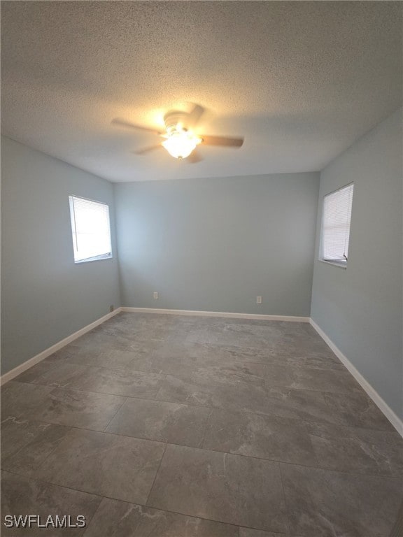 unfurnished room with ceiling fan and a textured ceiling