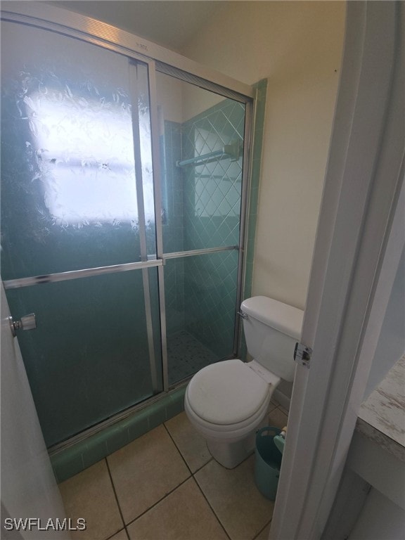 bathroom with a shower with door, toilet, and tile patterned floors