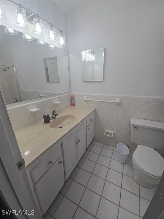 bathroom with tile walls, tile patterned flooring, vanity, and toilet