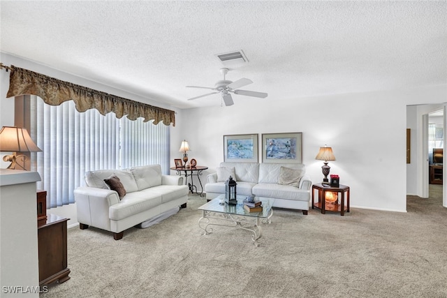 living room with a textured ceiling, ceiling fan, and light colored carpet