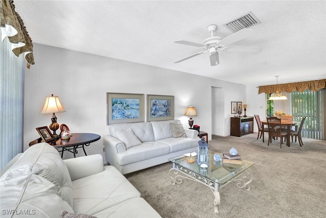 living room with ceiling fan with notable chandelier, a textured ceiling, and carpet flooring