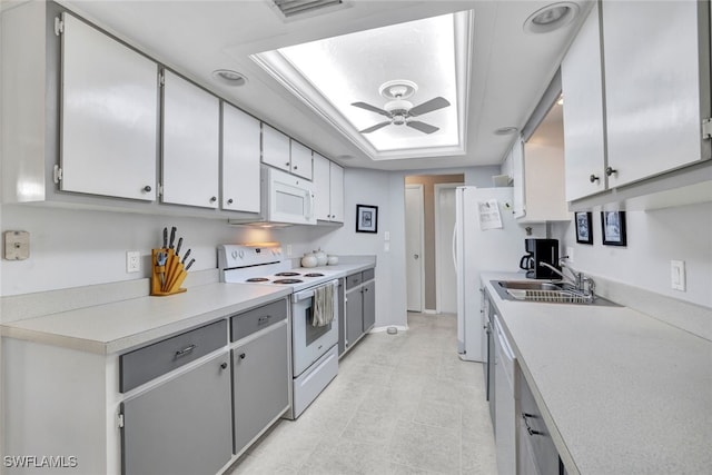 kitchen featuring white appliances, a tray ceiling, sink, and ceiling fan