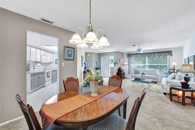 dining area featuring light colored carpet, a textured ceiling, and ceiling fan with notable chandelier