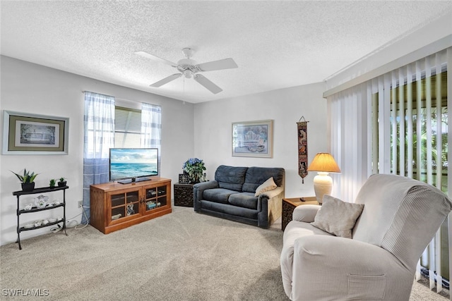 living room featuring ceiling fan, carpet flooring, and a textured ceiling