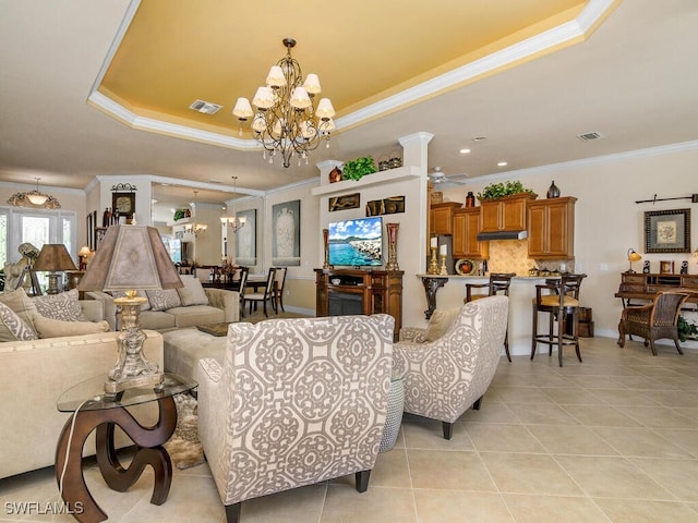 tiled living room with ornamental molding, ceiling fan with notable chandelier, and a raised ceiling