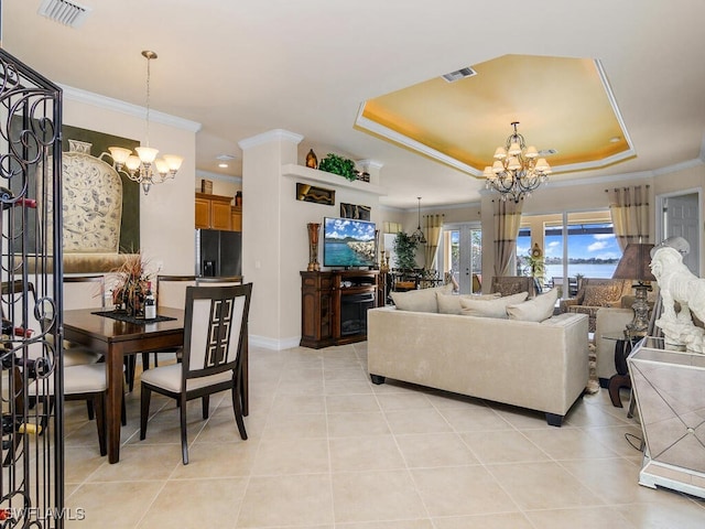 living room with light tile patterned floors, ornamental molding, a tray ceiling, and a chandelier