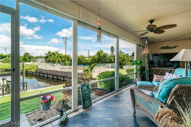 sunroom / solarium featuring a water view and ceiling fan