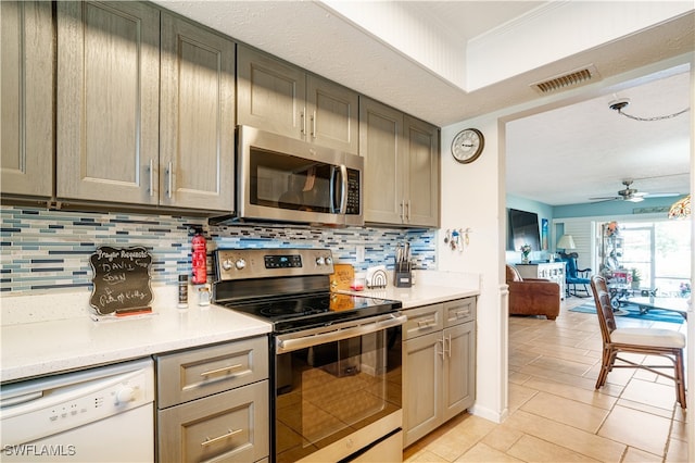 kitchen with light tile patterned flooring, appliances with stainless steel finishes, backsplash, and ceiling fan