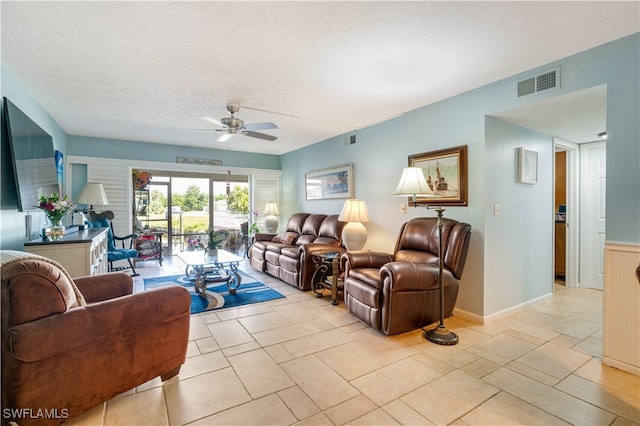 living room with ceiling fan and a textured ceiling