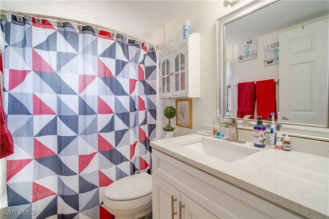 bathroom with vanity, a textured ceiling, curtained shower, and toilet