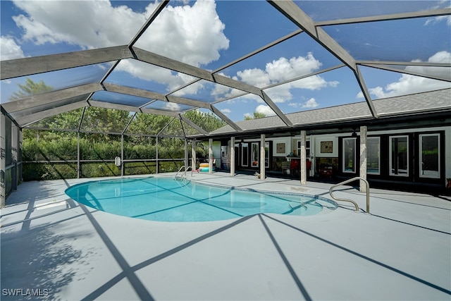 view of swimming pool with glass enclosure and a patio