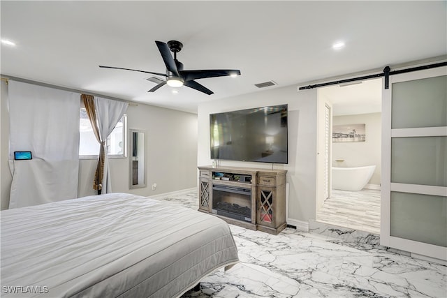 bedroom featuring ceiling fan, ensuite bathroom, and a barn door