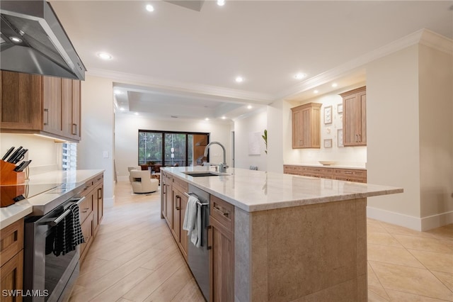 kitchen with wall chimney range hood, sink, a large island, light hardwood / wood-style floors, and crown molding