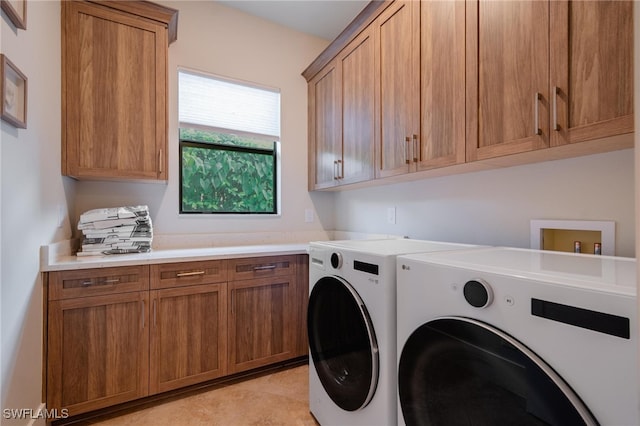 clothes washing area with washing machine and dryer and cabinets