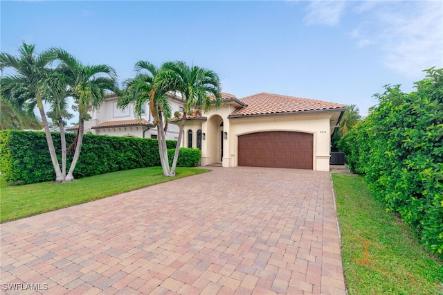 mediterranean / spanish home with a front yard, a garage, and central air condition unit