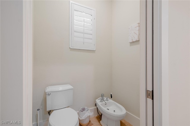 bathroom with toilet, a bidet, and tile patterned flooring