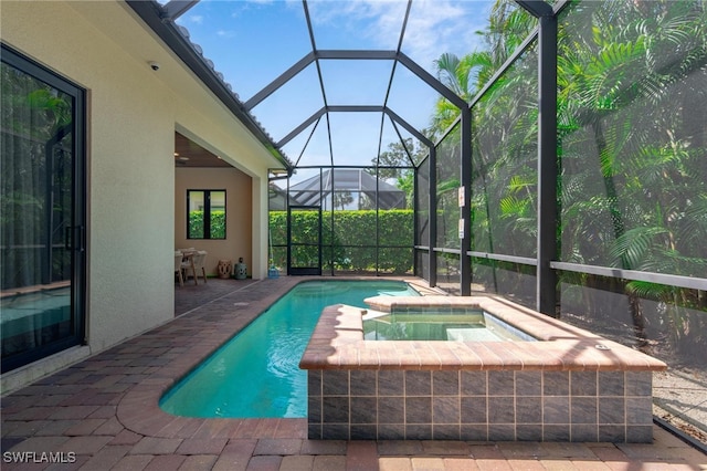 view of pool with an in ground hot tub, a patio, and glass enclosure