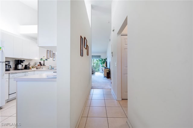 hallway featuring a towering ceiling and light tile patterned flooring