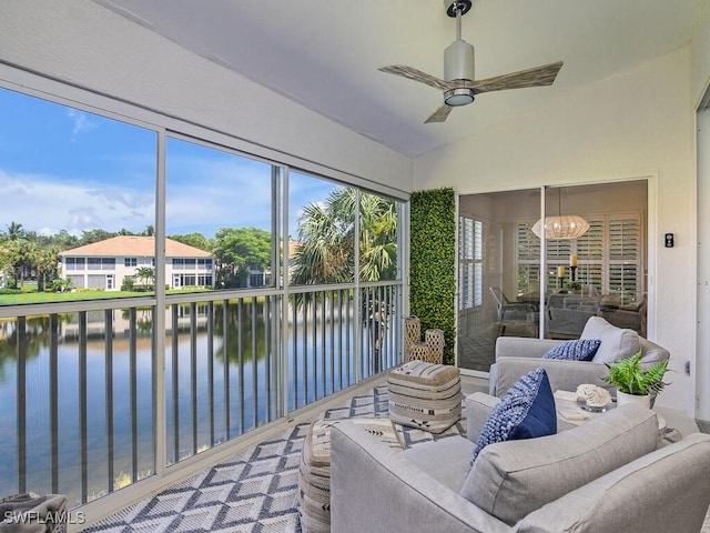 sunroom / solarium featuring ceiling fan with notable chandelier, a water view, and lofted ceiling