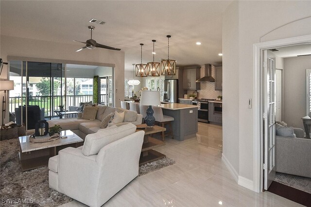 living room with ceiling fan with notable chandelier and sink