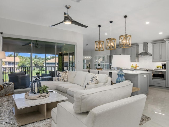 living room with recessed lighting, marble finish floor, and ceiling fan with notable chandelier