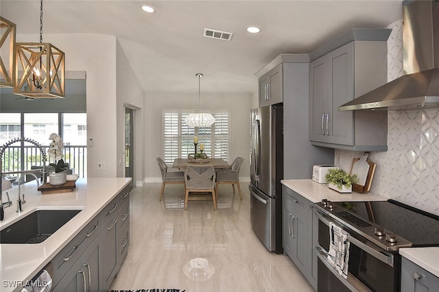 kitchen featuring pendant lighting, a notable chandelier, wall chimney exhaust hood, and stainless steel appliances