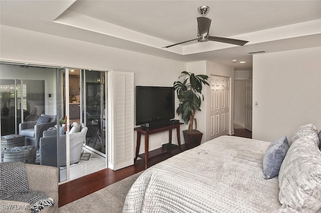 bedroom featuring ceiling fan, access to exterior, a raised ceiling, and dark wood-type flooring